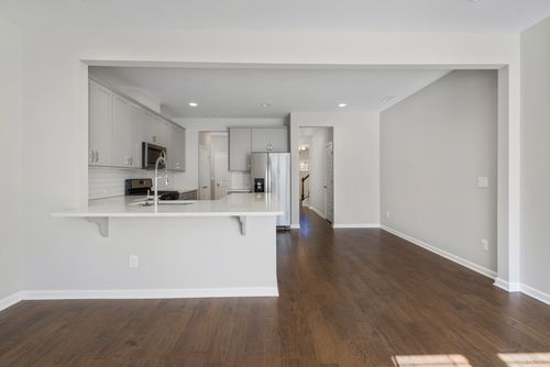 Free Bright, empty modern kitchen featuring hardwood floors and white cabinetry. Stock Photo