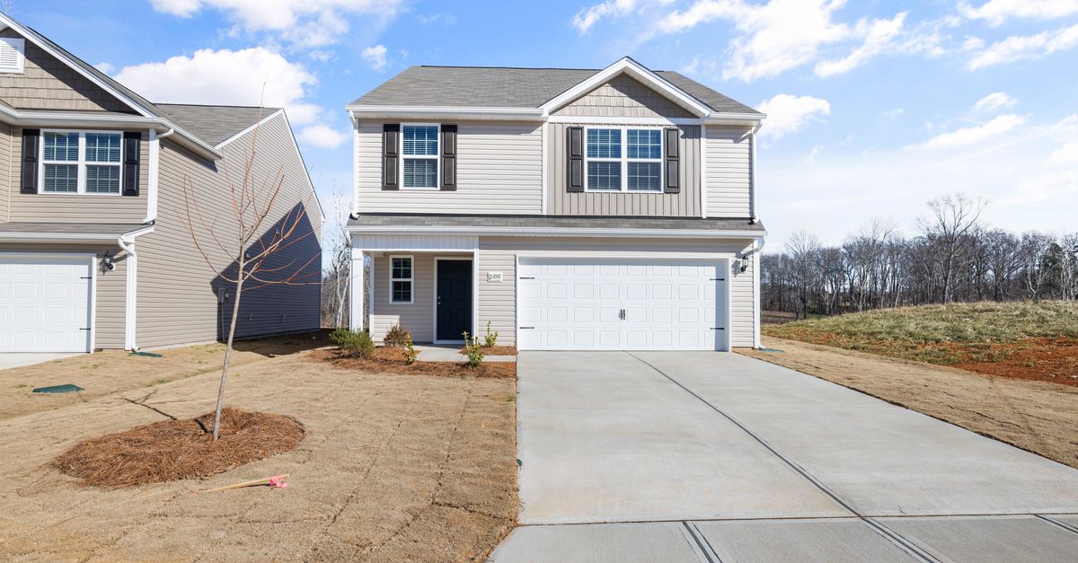 Contemporary two-story home with a large driveway in a suburban setting.