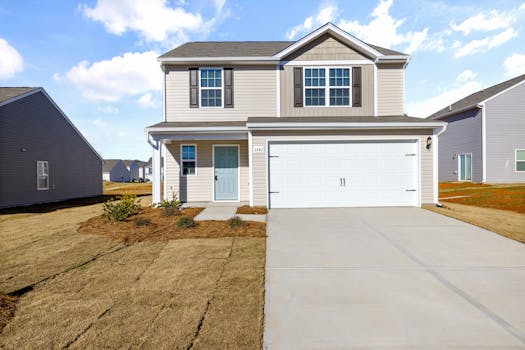 Two-story suburban house with large driveway and clear blue sky.