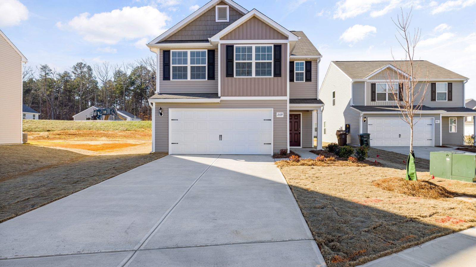 New plain concrete driveway leading to a double garage