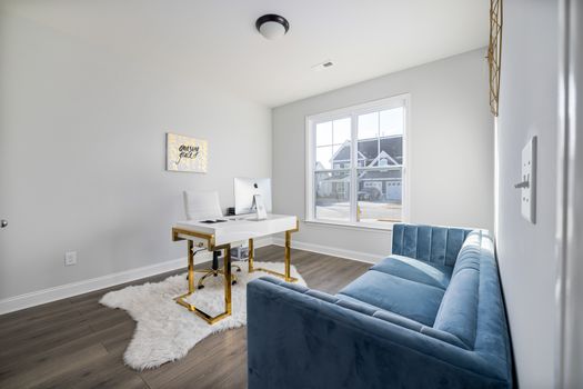 A stylish modern home office featuring a velvet couch and sleek desk with natural light.