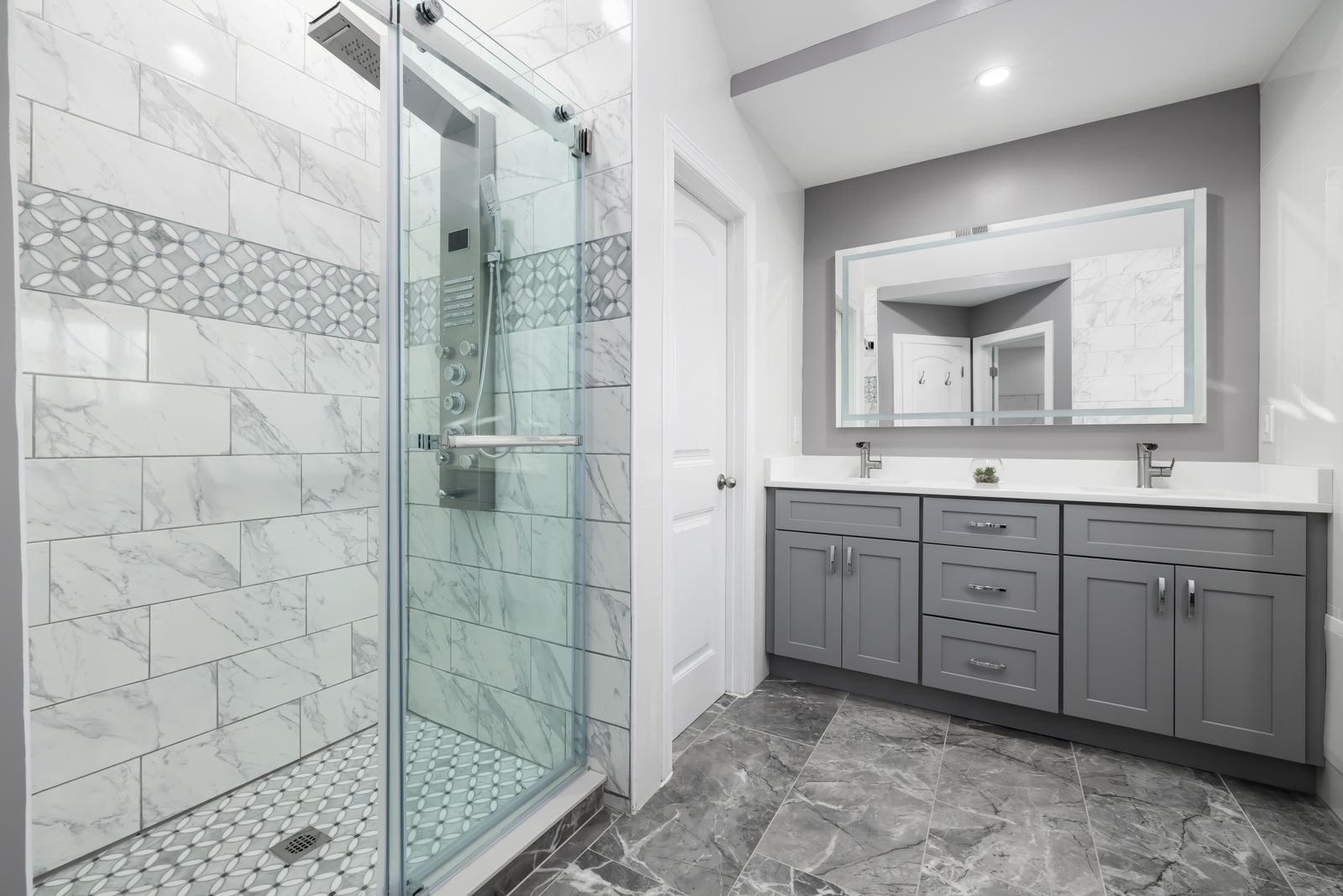 Bathroom with grey cabinets and marble tiled shower