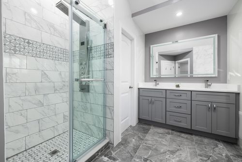 Free Luxurious modern bathroom featuring grey cabinets and a marble-tiled shower. Stock Photo