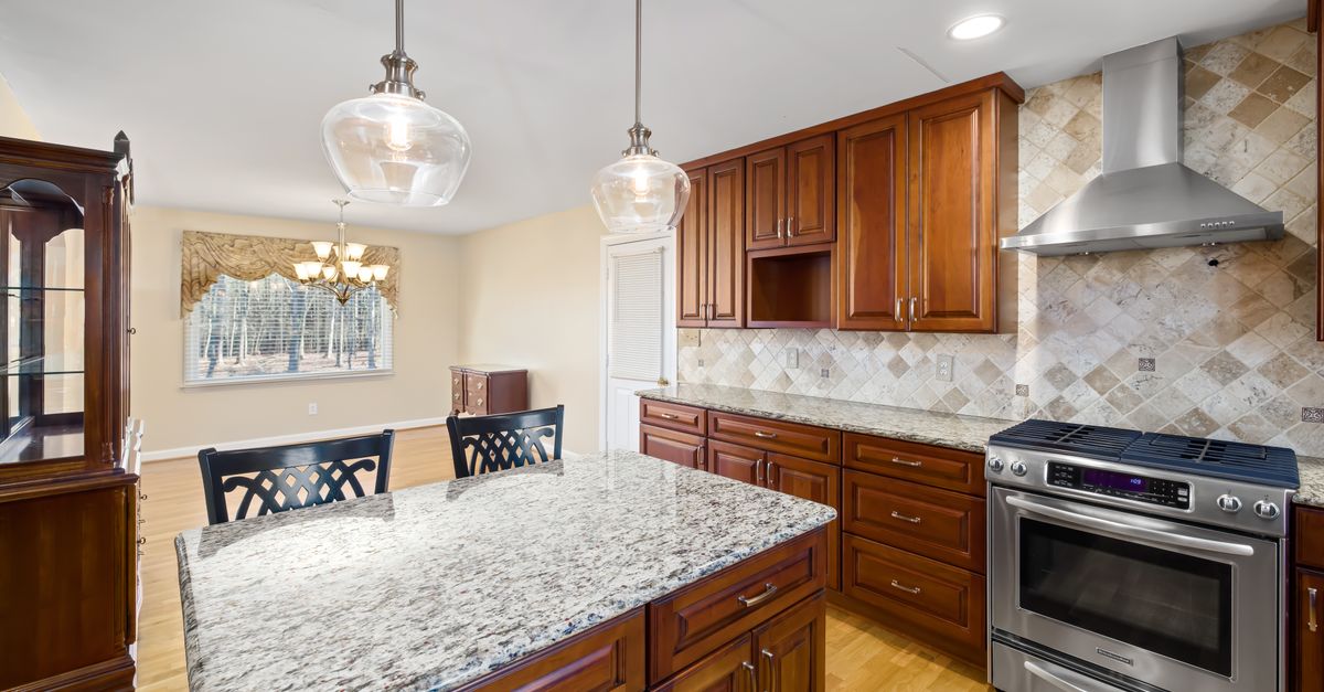 Spacious modern kitchen featuring granite countertops and wooden cabinets.