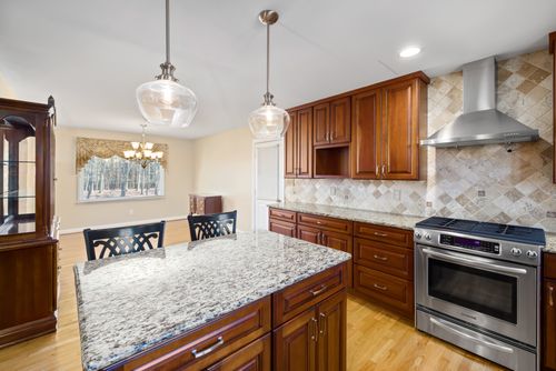 Free Spacious modern kitchen featuring granite countertops and wooden cabinets. Stock Photo