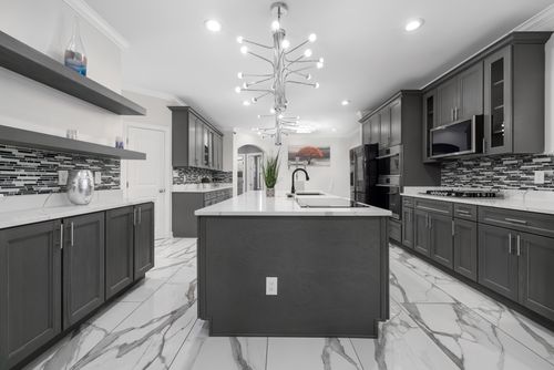 Free Spacious modern kitchen with grey cabinets and marble floors, featuring contemporary lighting. Stock Photo
