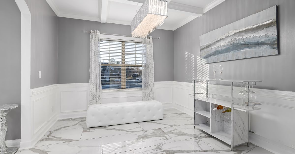 Bright minimalist room with luxury marble flooring and modern decor, featuring chandelier and abstract art.