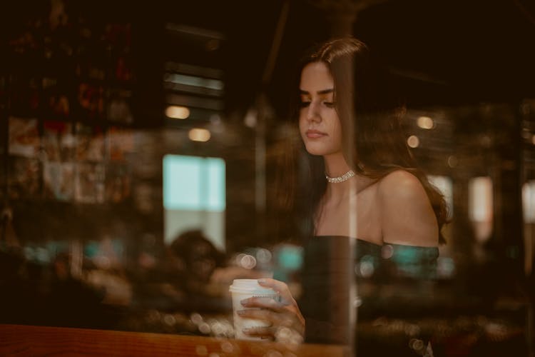 Woman Sitting By Cafe Table Seen Through Window