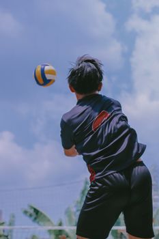 Dynamic shot of a teenager playing volleyball outdoors in Central Java, Indonesia.