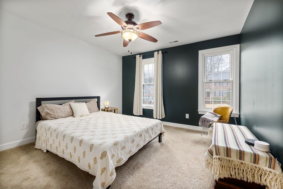 Bright and cozy modern bedroom with a comfortable bed, ceiling fan, and large windows.