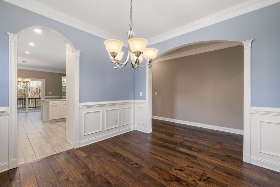 A chic dining room featuring a central chandelier and elegant wooden flooring.