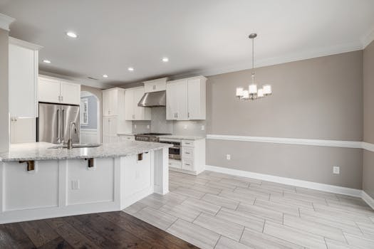 Bright modern kitchen with granite island and stainless steel appliances.