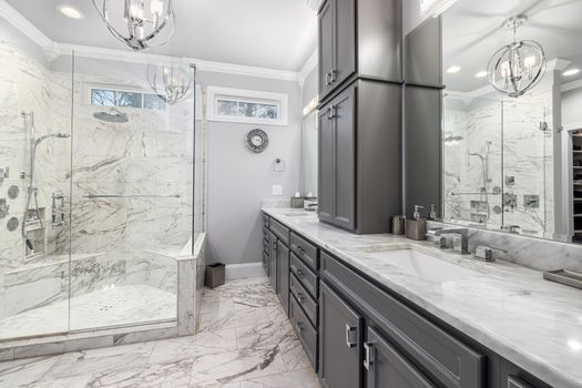 Elegant contemporary bathroom with marble surfaces and gray cabinets.