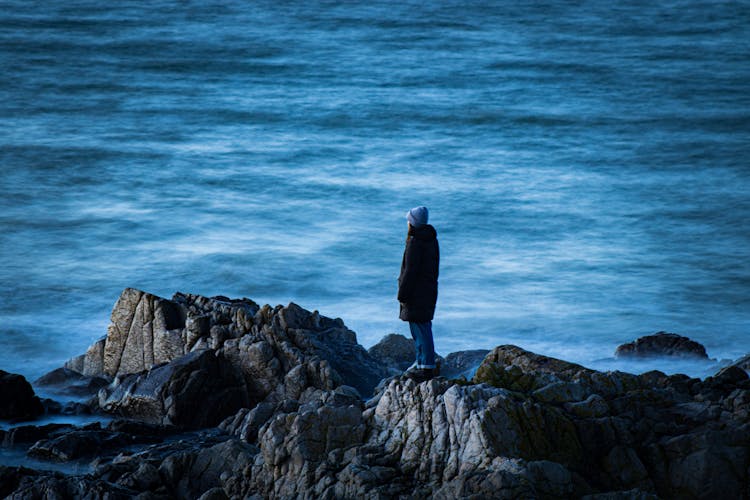 A Person Standing On The Rock Near The Sea 