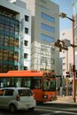 Orange Bus on Road Near Tall Buildings