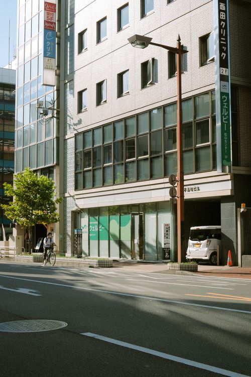 Free Urban city street with modern buildings and a cyclist passing by on a sunny day. Stock Photo