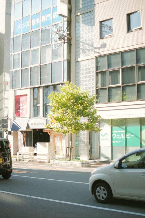 Free Street view of modern buildings with cars in a bustling city during the day. Stock Photo