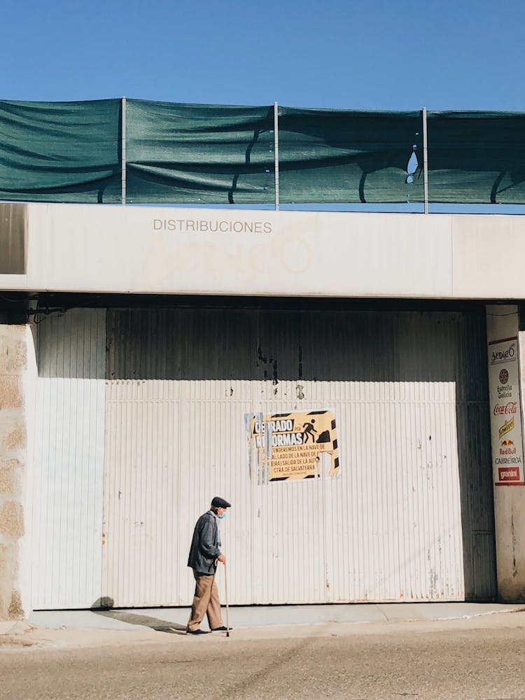 Elderly Man Walking By Warehouse