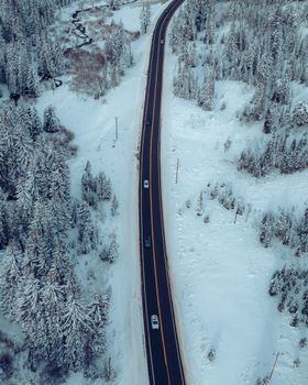 Stunning aerial shot of a snowy road winding through a winter forest.