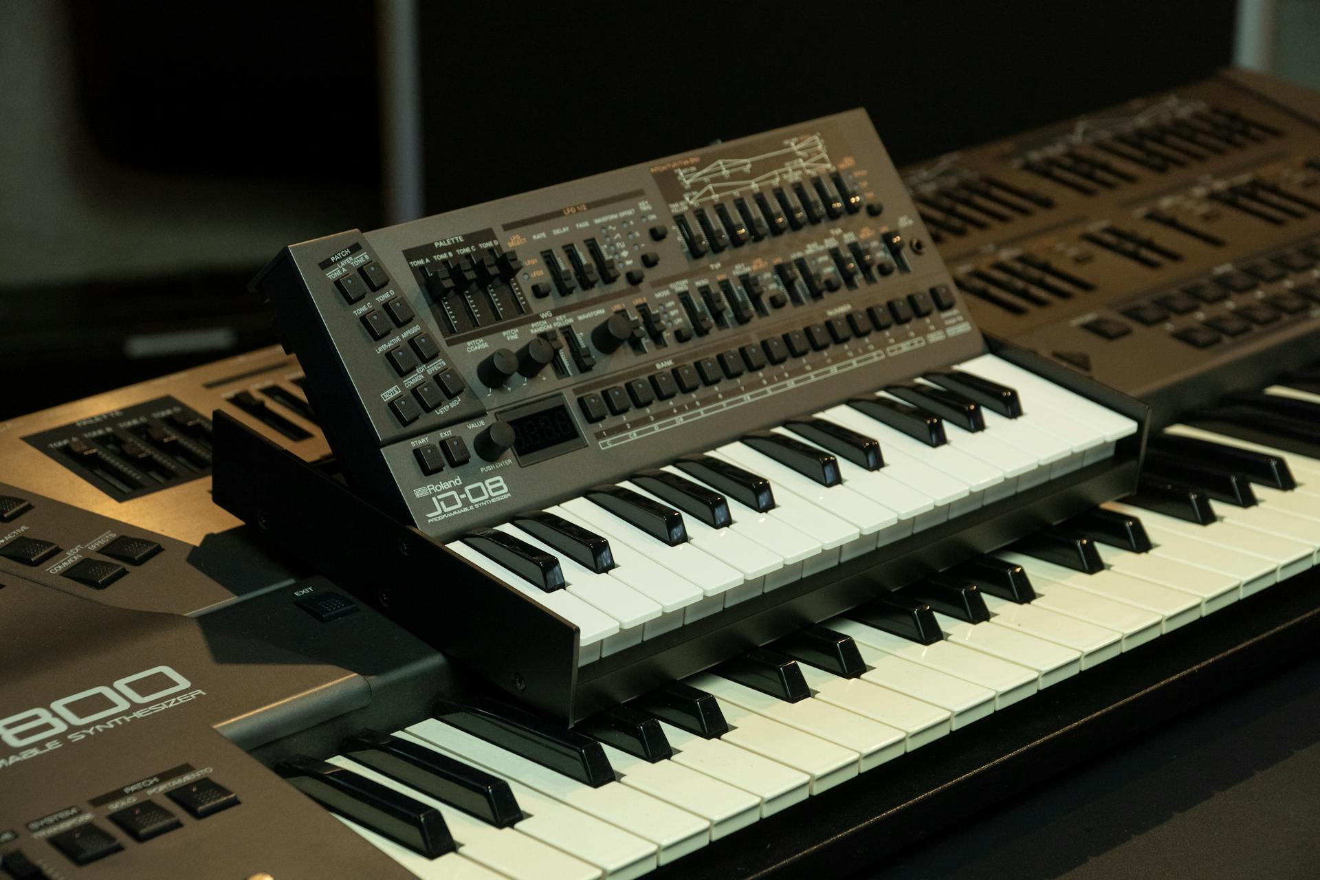 Stacked electronic synthesizer keyboards with control panels for music production.