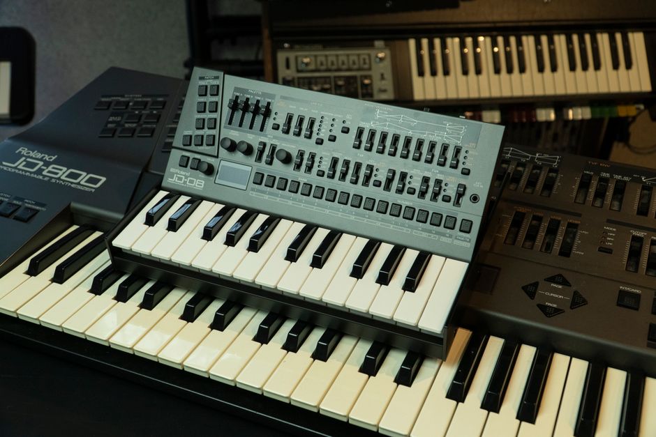 Producer working with audio files at a synthesizer keyboard