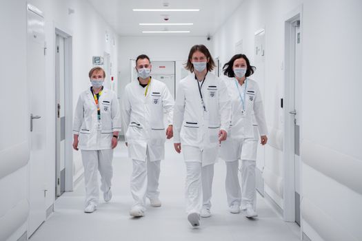 Medical team walking confidently in a hospital corridor, wearing face masks and white coats, symbolizing teamwork and healthcare dedication.