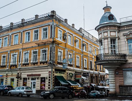 Urban street view with historic architecture, vibrant colors, and parked cars in a bustling city.