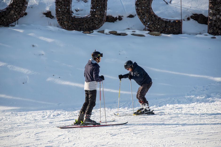 Two adult skiers in full gear enjoying a winter day on the slopes, capturing the essence of winter sports fun.