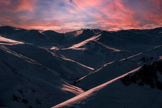 A dramatic view of snow-covered mountains under a vibrant twilight sky.