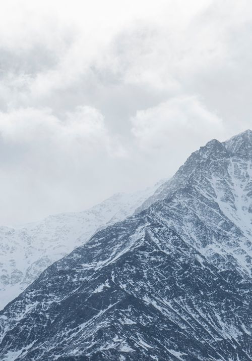 Free Winter landscape of snow-covered mountains and clouds, perfect for nature backgrounds. Stock Photo