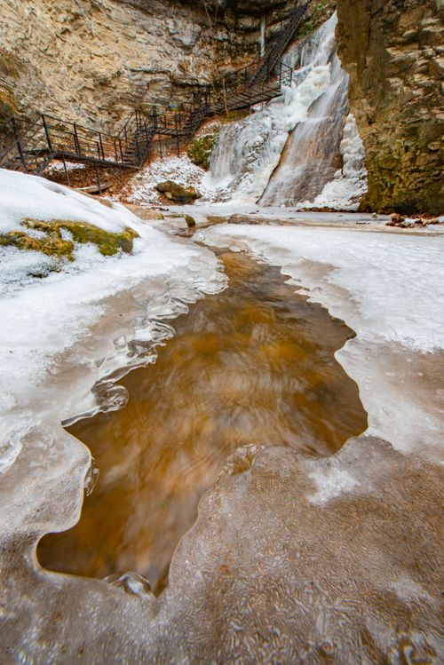 Free A picturesque frozen waterfall and icy creek in a rocky winter terrain. Stock Photo