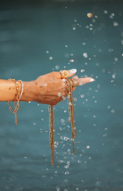 Womans Hand Holding Jewellery Over Water 