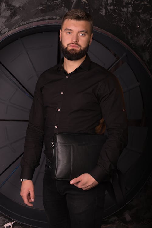 A Man in Black Long Sleeves Holding Black Leather Bag