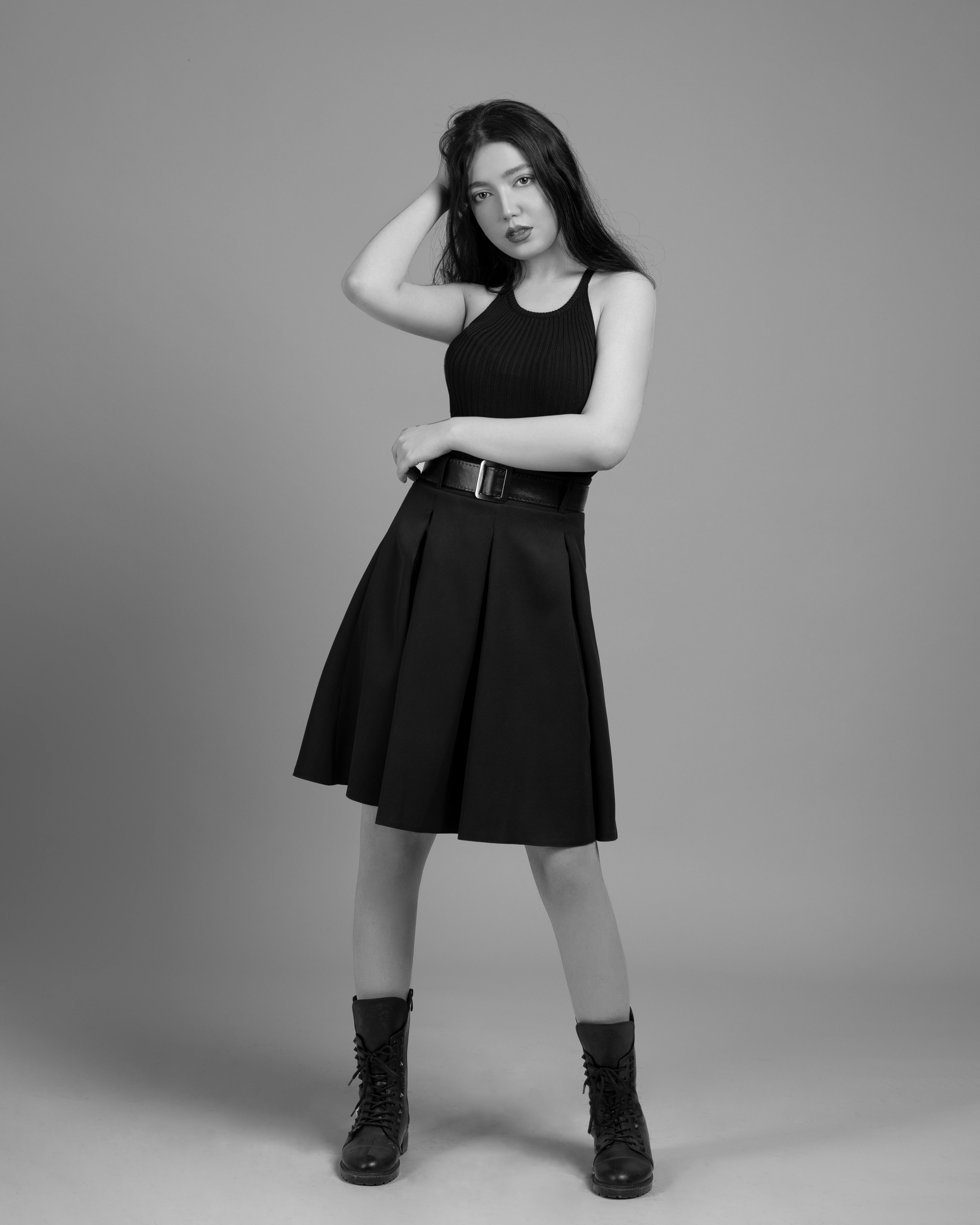 Stylish black and white portrait of a woman in a studio setting wearing a black dress.