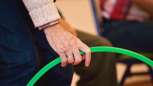 Close-up of an Elderly Man Hand Holding a Green Ring 