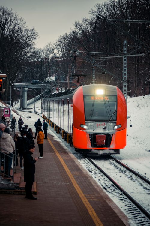 Free Red train arriving at a snow-covered station in Kaliningrad, Russia during winter. Commuters on the platform. Stock Photo