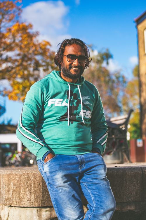 Free Smiling man with sunglasses and green sweatshirt enjoying a sunny day outdoors. Stock Photo