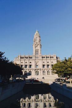 Stunning vertical shot of Porto Town Hall with reflection in water, set against a clear blue sky.