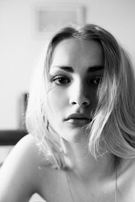 Elegant black and white close-up portrait of a young blonde woman indoors.