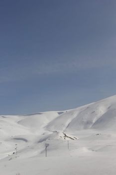 Expansive snow-covered mountain under clear blue sky, perfect for winter themes.