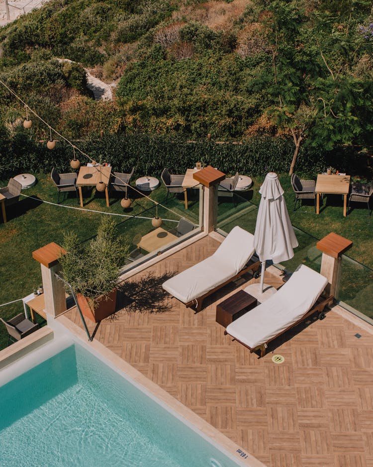 Outdoor Lounge Chairs On A Deck Near A Swimming Pool