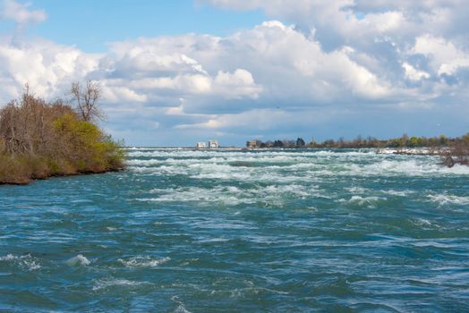 Captivating view of Niagara River with rippling water under a partly cloudy sky at Niagara Falls.