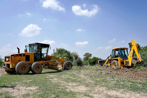 Yellow and Black Heavy Equipment on Green Grass Field Under Blue Sky