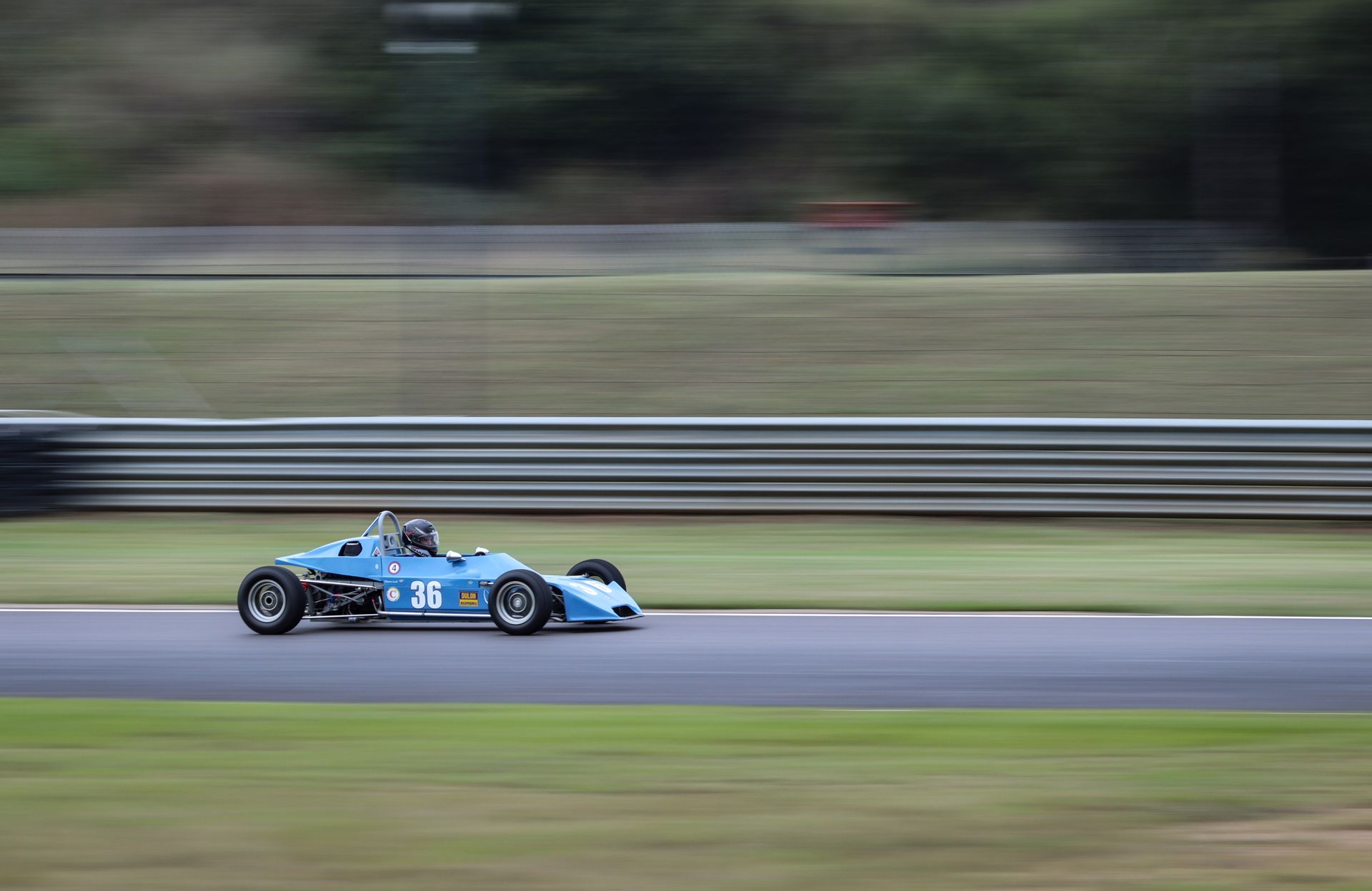 A blue race car speeds along a track, capturing motion and excitement on a racing circuit.