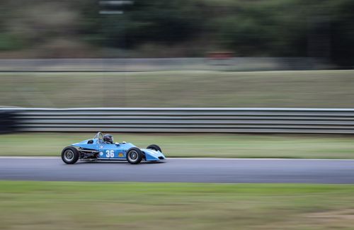 Free A blue race car speeds along a track, capturing motion and excitement on a racing circuit. Stock Photo