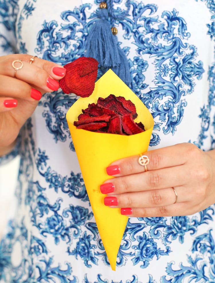 Hands Eating Red Chips From Yellow Cone