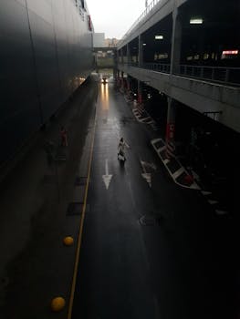 Rainy day view of a person walking in a dimly lit urban parking area.