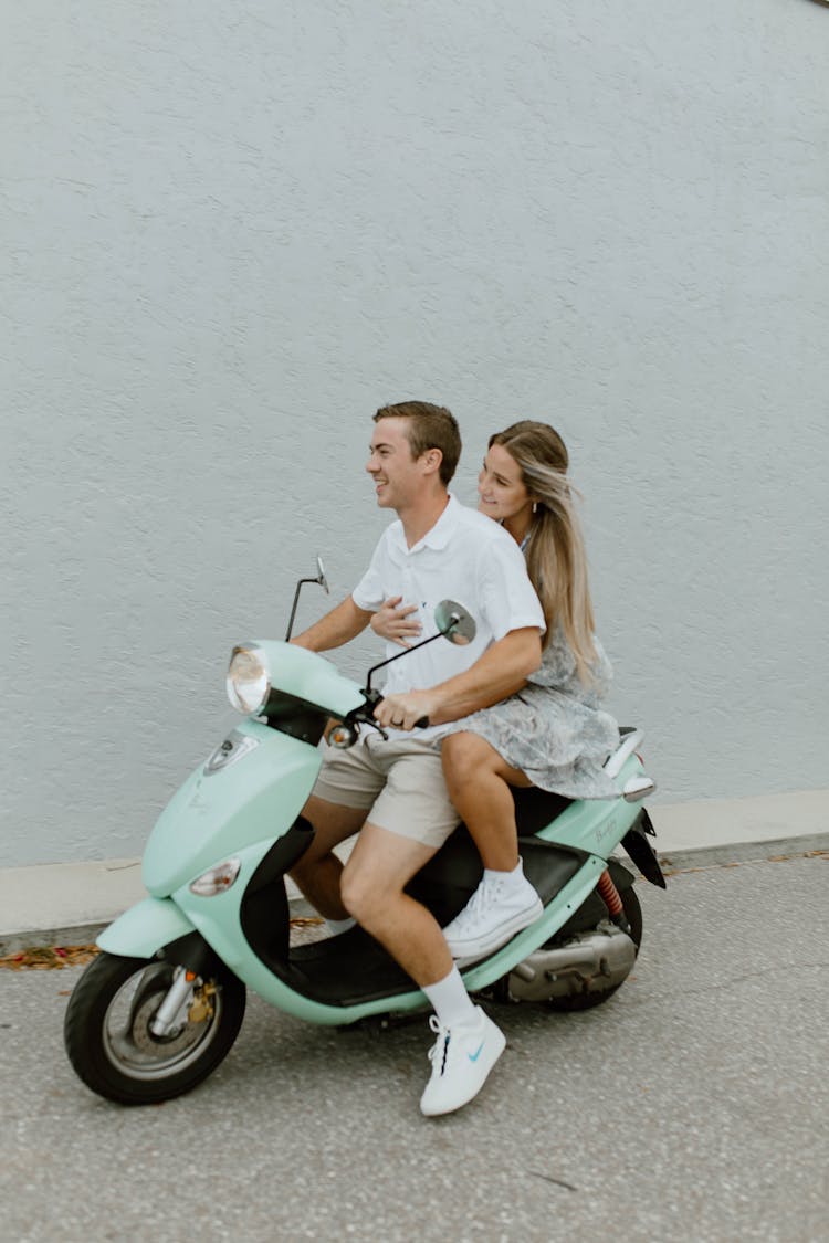 A Couple Riding A Scooter