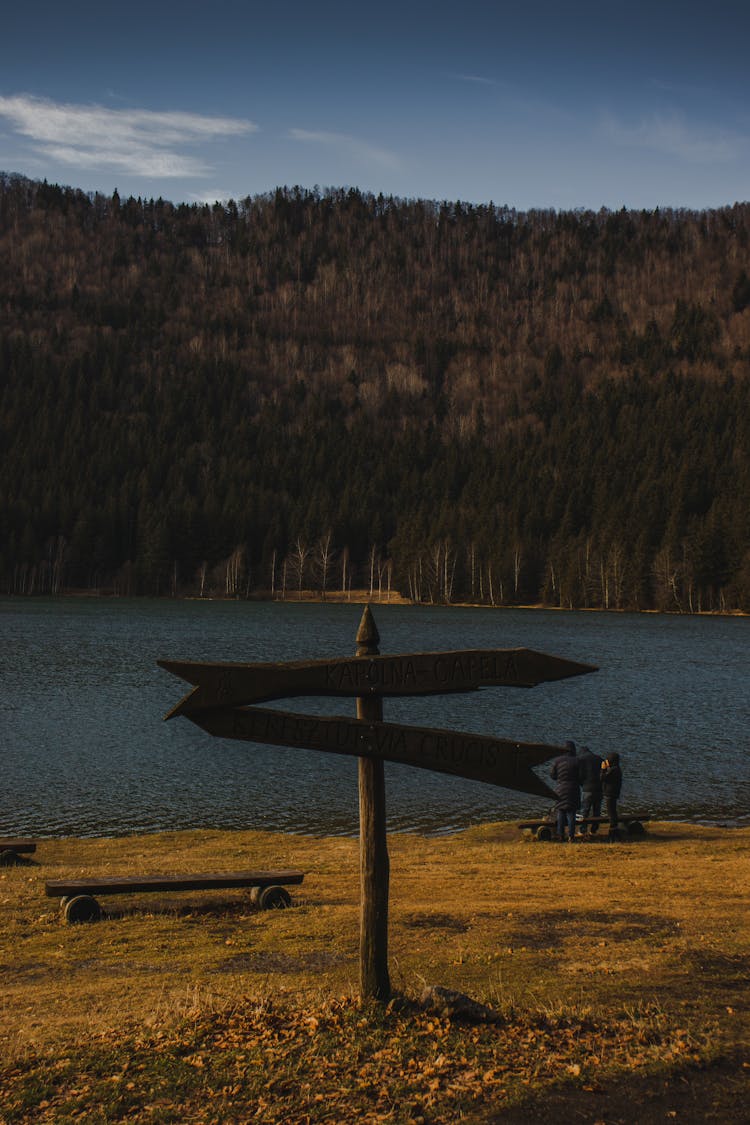 Wooden Arrow Sign In Front Of A Lake