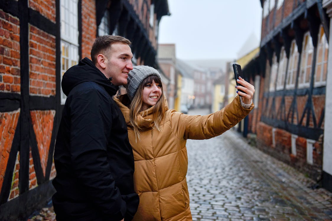 Free Man and Woman In Winter Jackets Taking Selfie Stock Photo